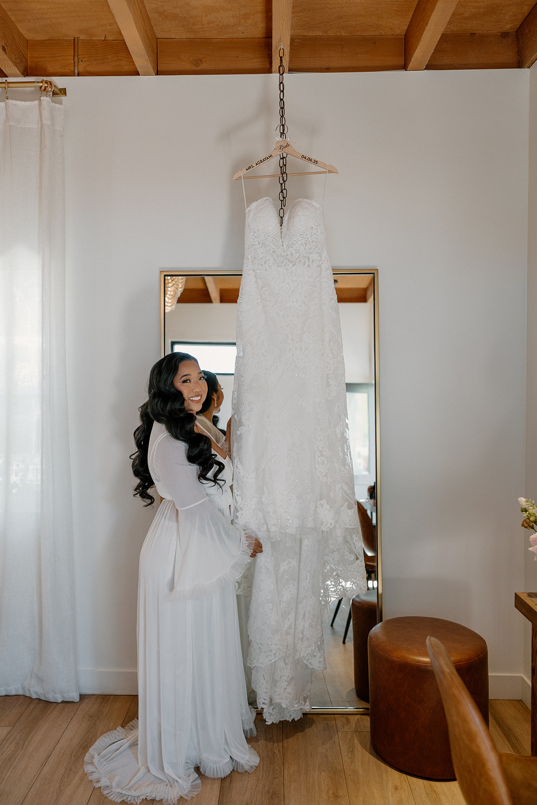 Bride smiling at her gown inside the getting-ready space at The Paseo wedding venue, full of natural light and warm tones.