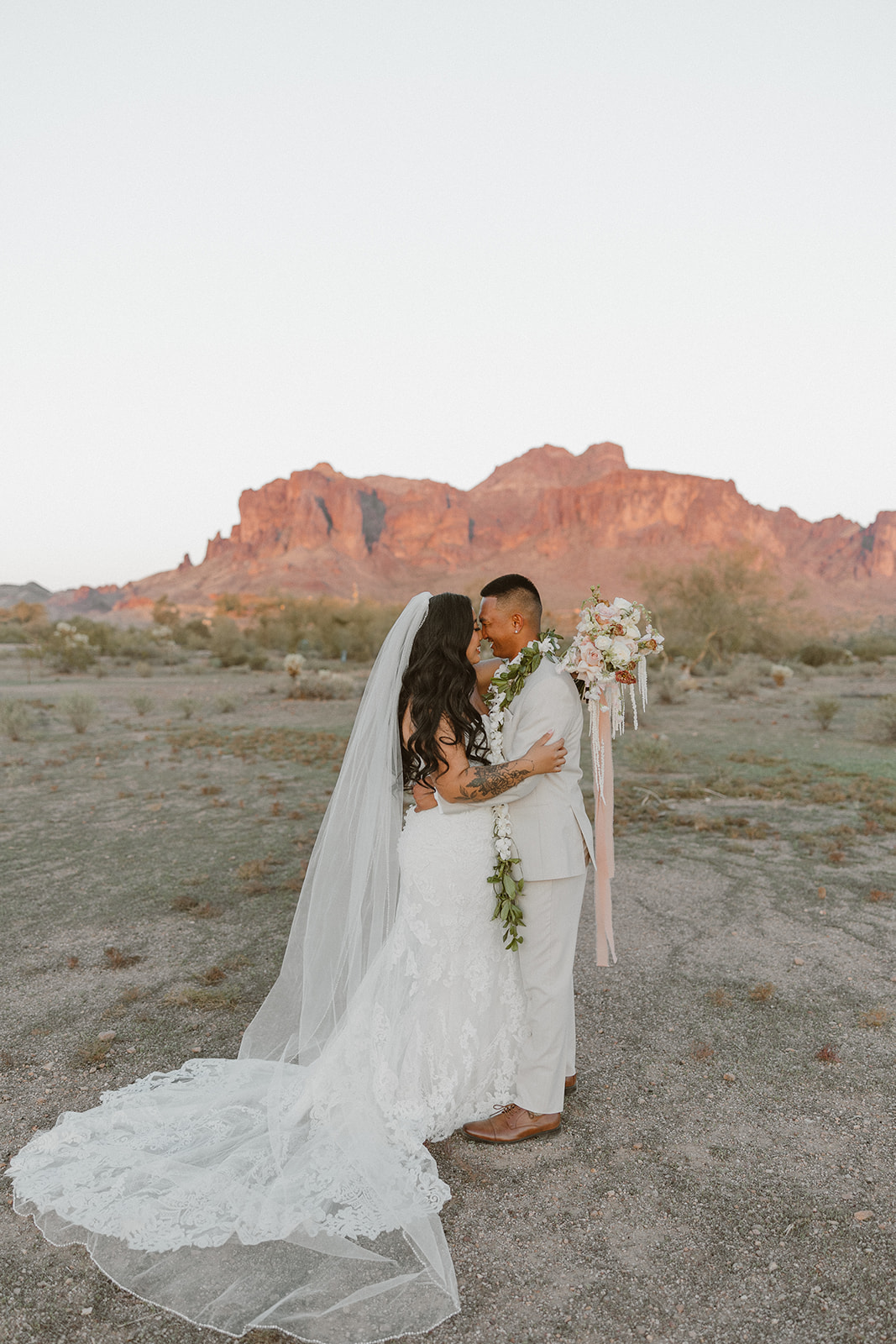 Bride and groom share a quiet moment in the desert with the Superstition Mountains glowing behind them.