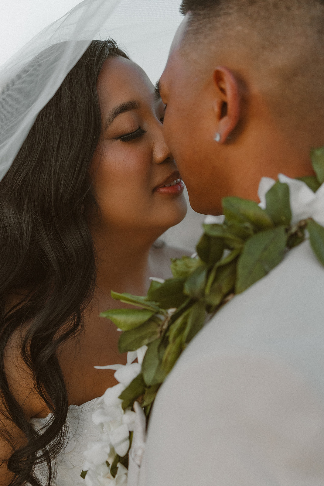 Close-up of the couple mid-kiss under the bride’s veil, showing off lei details and that soft post-ceremony glow at The Paseo wedding.