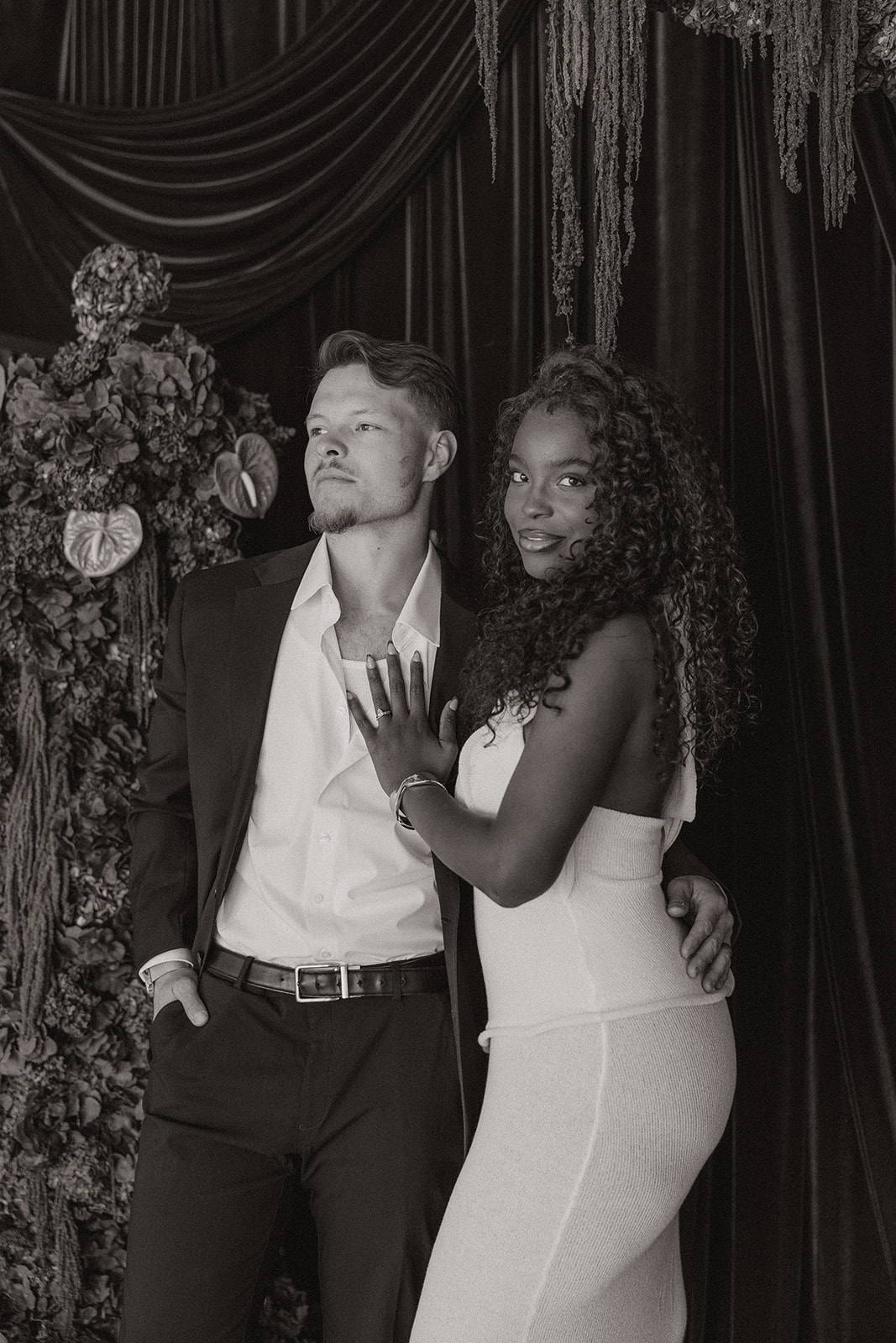 Black and white photo of couple embracing while wearing classic engagement photo outfits. 