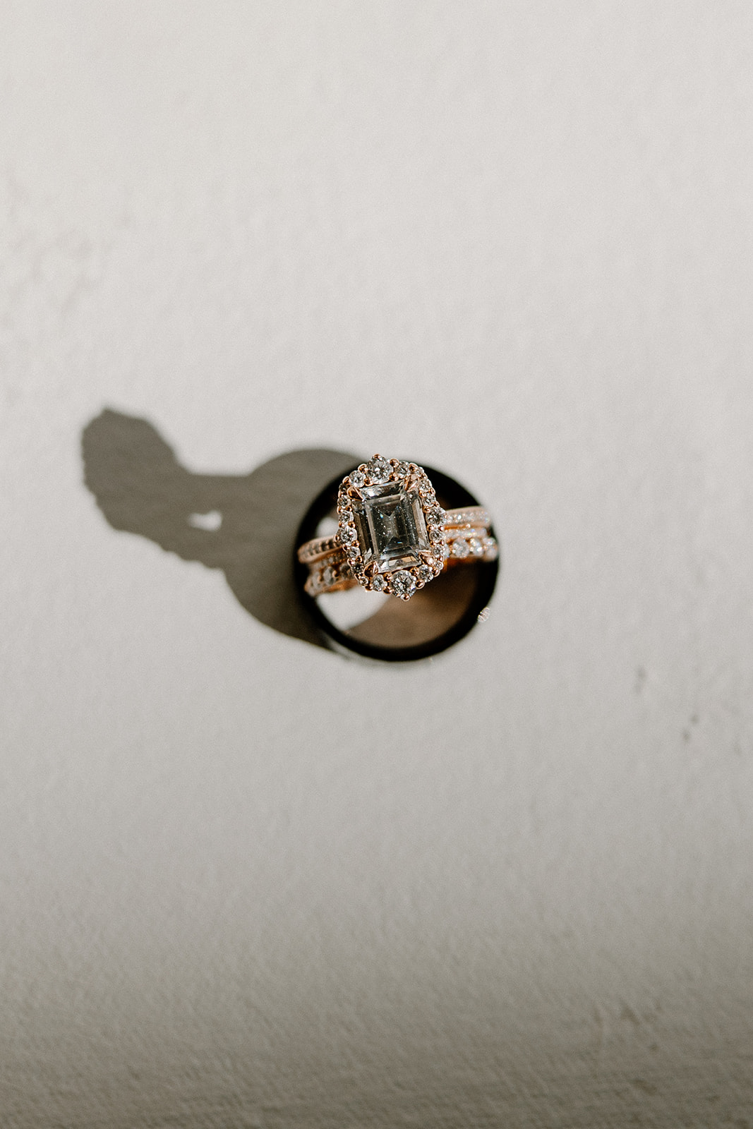 Emerald-cut engagement ring and wedding band styled in directional natural light.