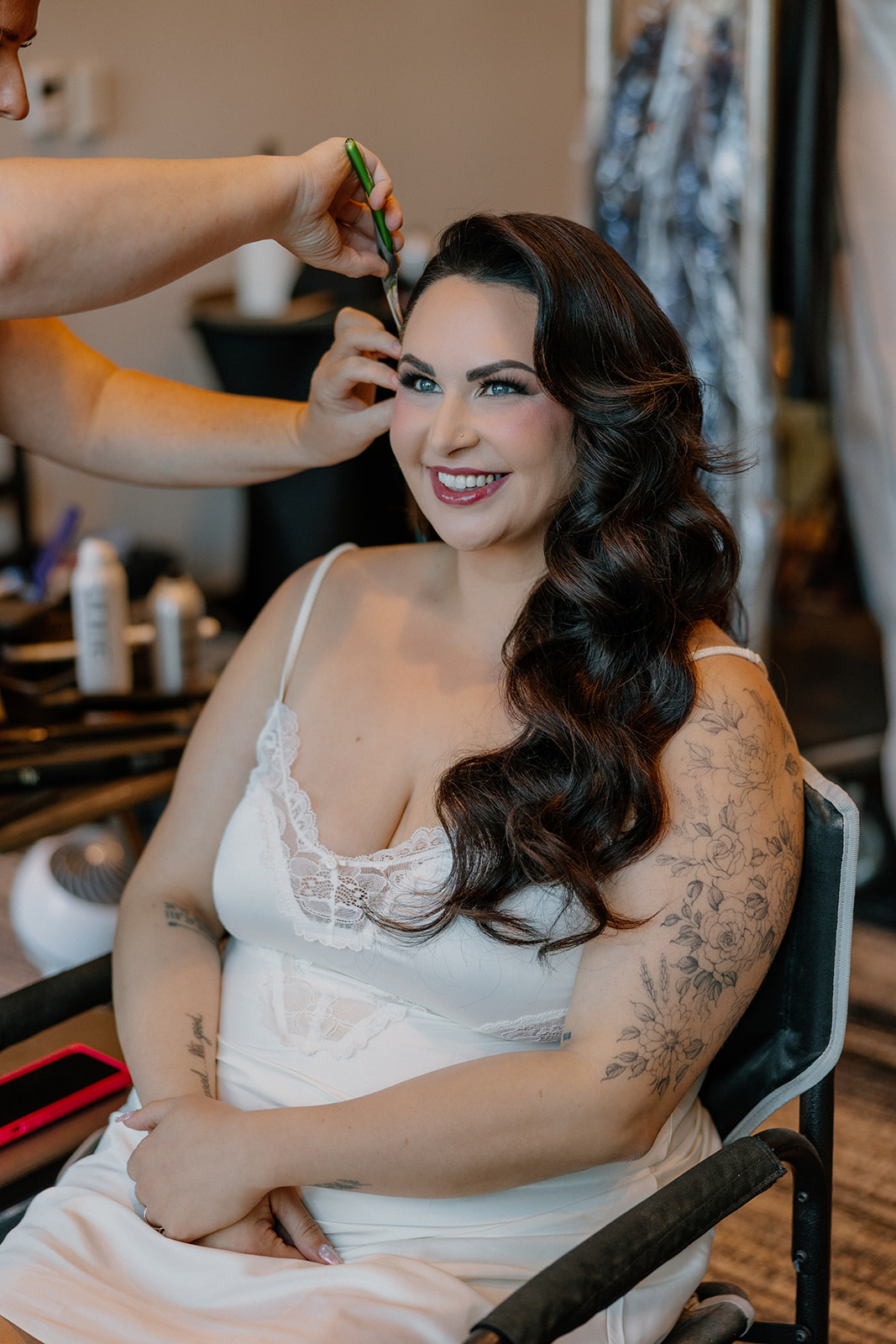 Bride smiling during hair and makeup while getting ready in the bridal suite before the ceremony.