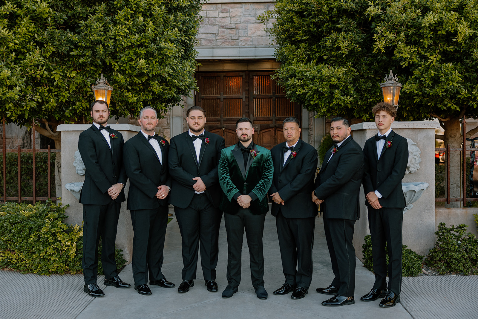 Groom and groomsmen posing in front of stone architecture at a wedding venue in Chandler.