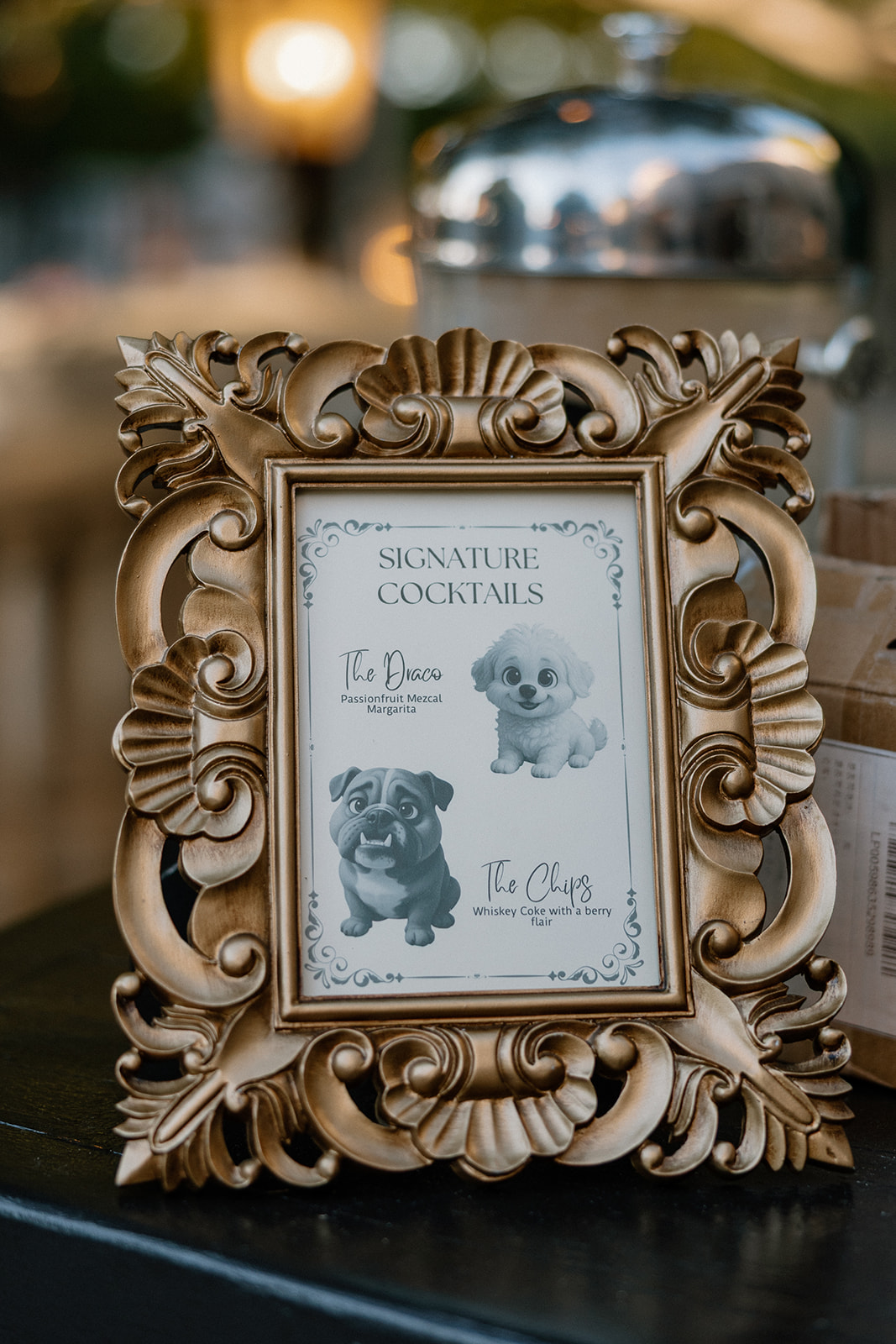 Framed signature cocktail sign featuring the couple’s dogs displayed during cocktail hour at a wedding venue in Chandler.