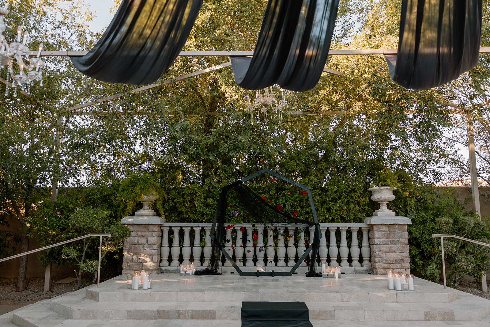 Ceremony setup with black geometric arch, candles, and stone balustrade at a wedding venue in Chandler.