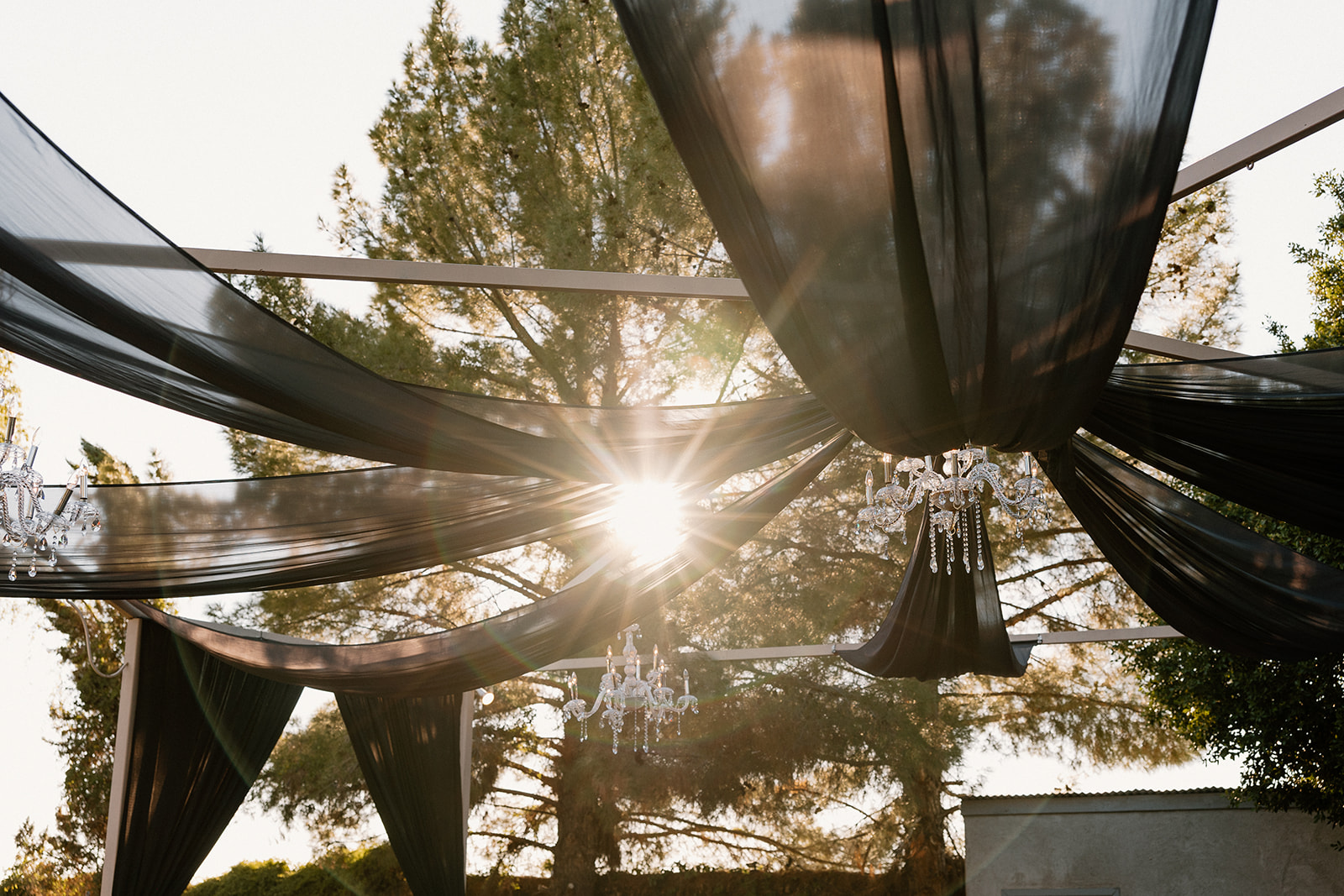 Black draping and chandeliers overhead as Arizona sunlight filters through the courtyard at this wedding venue in Chandler.