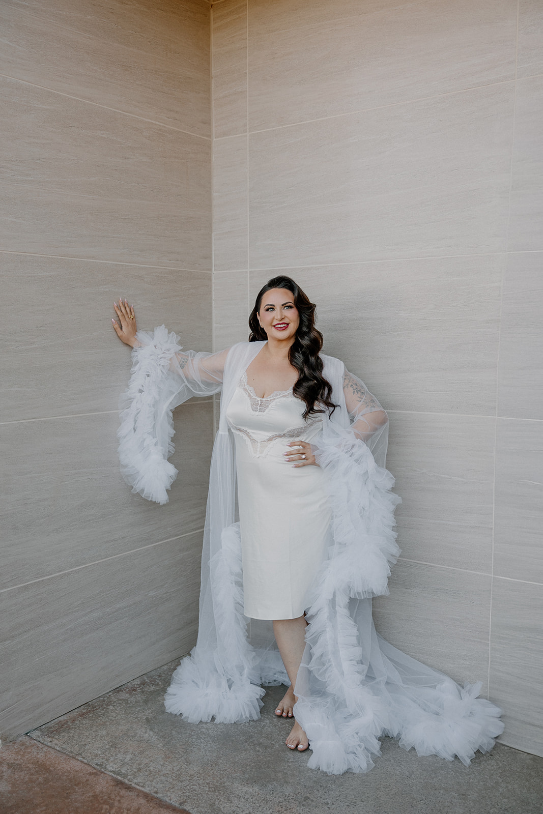 Bride in sheer feather-trimmed robe posing in soft natural light at this wedding venue in Chandler.