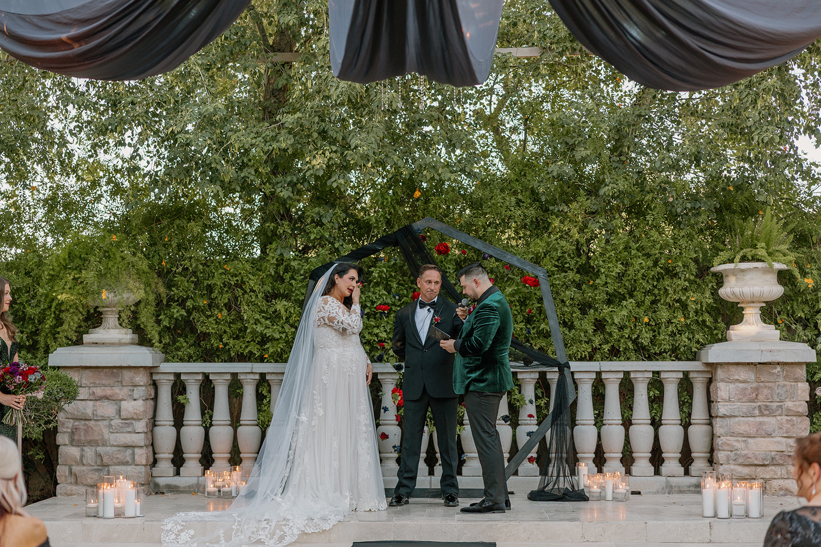 Outdoor ceremony beneath black draping and chandeliers at a wedding venue in Chandler.