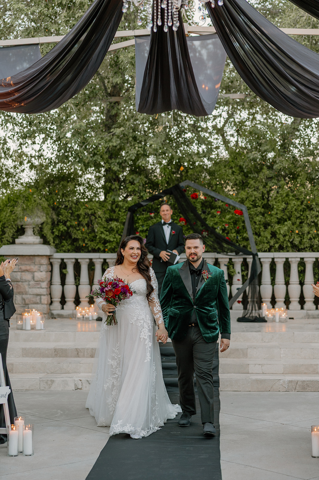 Newlyweds walking hand in hand down the aisle after their ceremony as guests applaud.