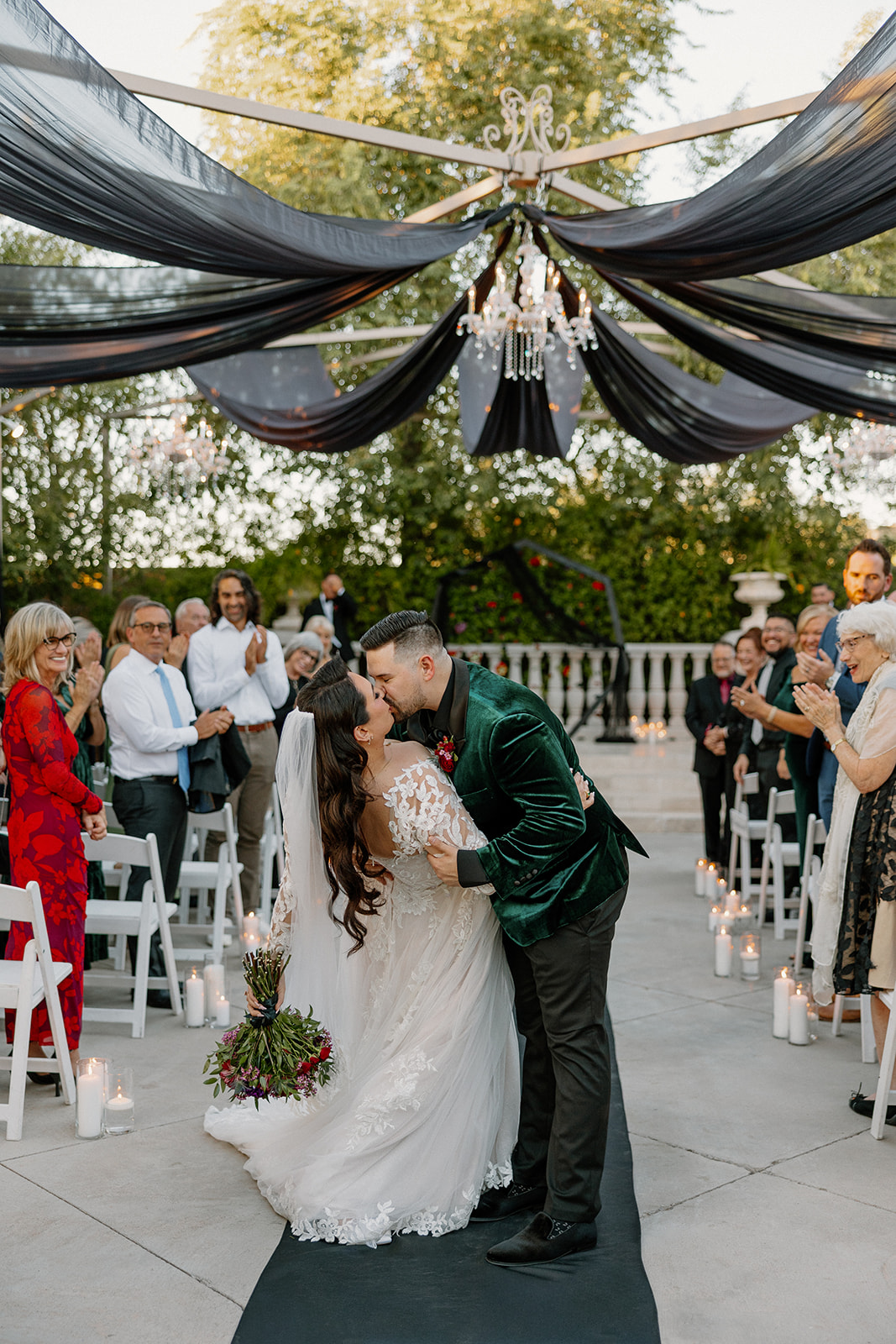 Bride and groom sharing their first kiss beneath black draping at a wedding venue in Chandler.