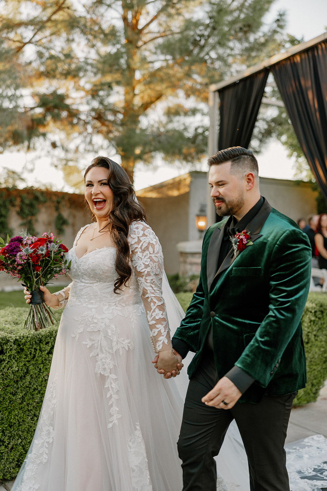 Newly married couple holding hands and smiling during their ceremony exit at a wedding venue in Chandler.