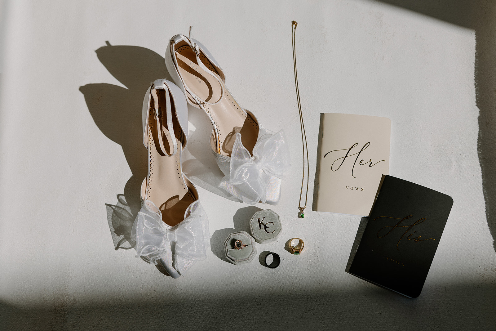 Wedding details including bow heels, vow books, rings, and jewelry styled in natural light at this wedding venue in Chandler.