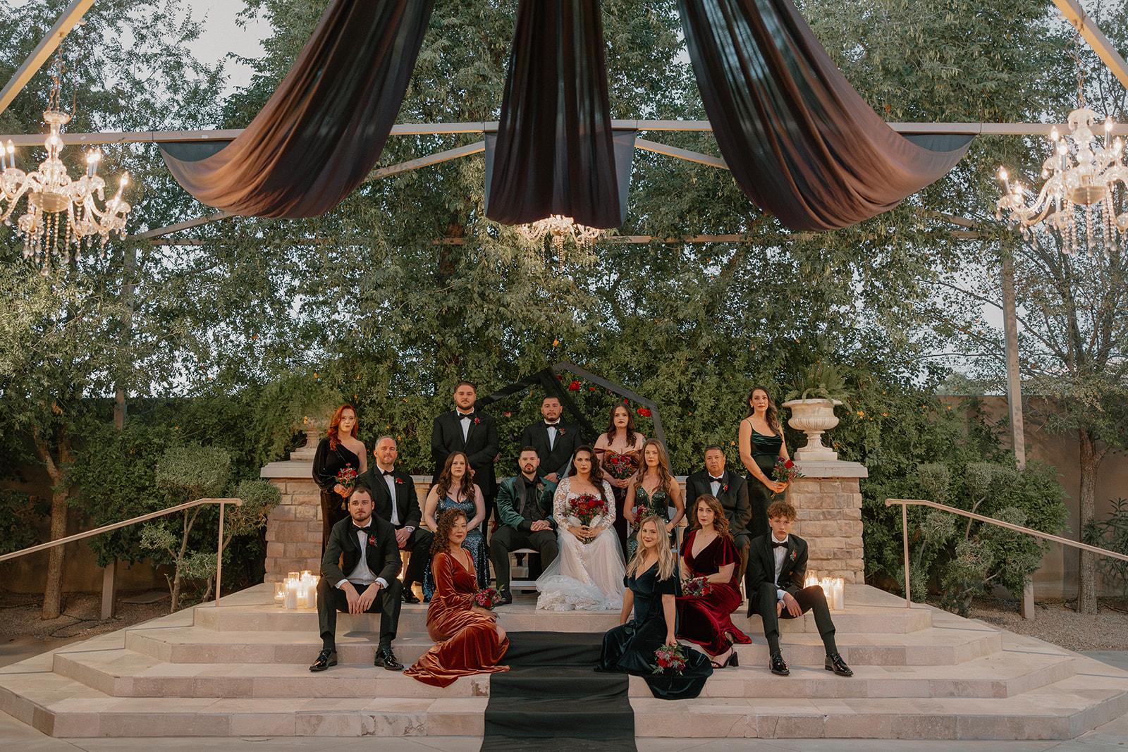 Wedding party portrait under black draping and chandeliers in the courtyard of this wedding venue in Chandler.