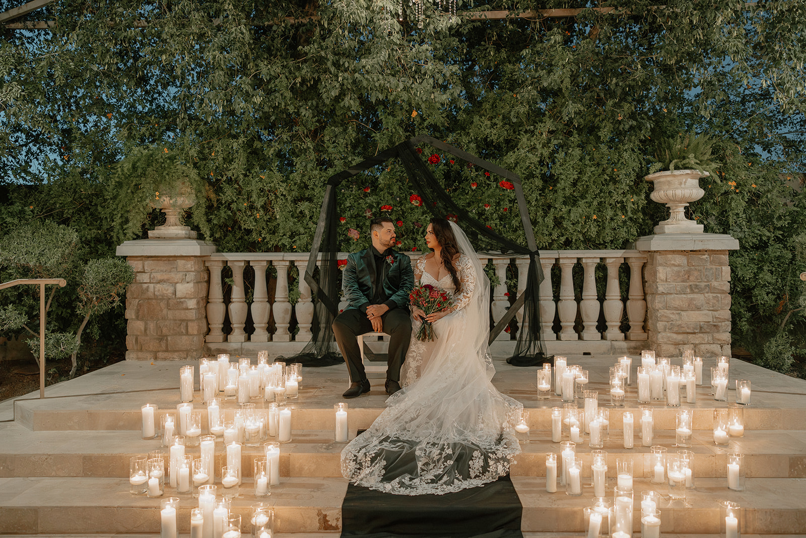 Bride and groom seated among candlelight on stone steps at a wedding venue in Chandler at dusk.