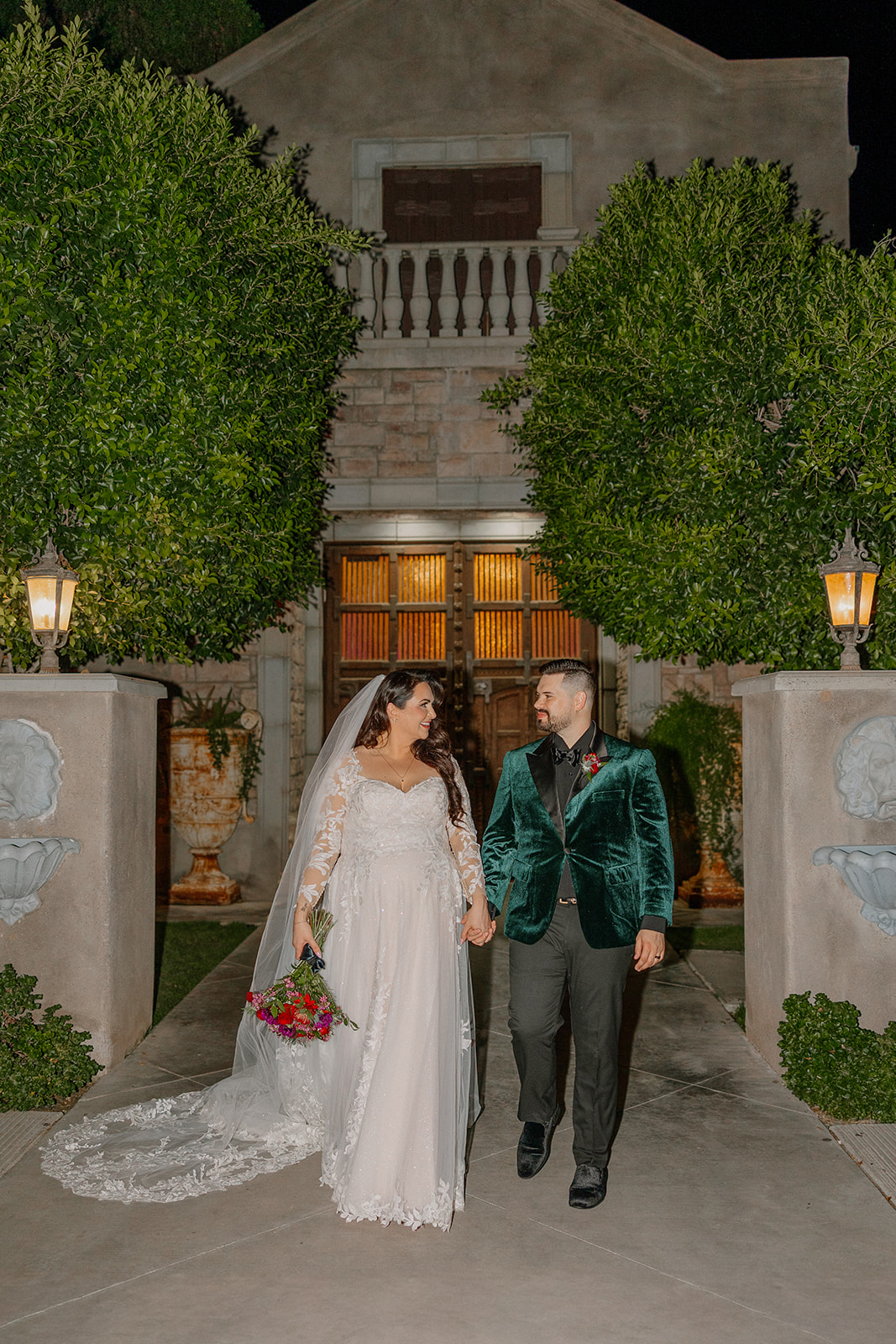 Bride and groom walking hand in hand at night outside this wedding venue in Chandler with soft exterior lighting.