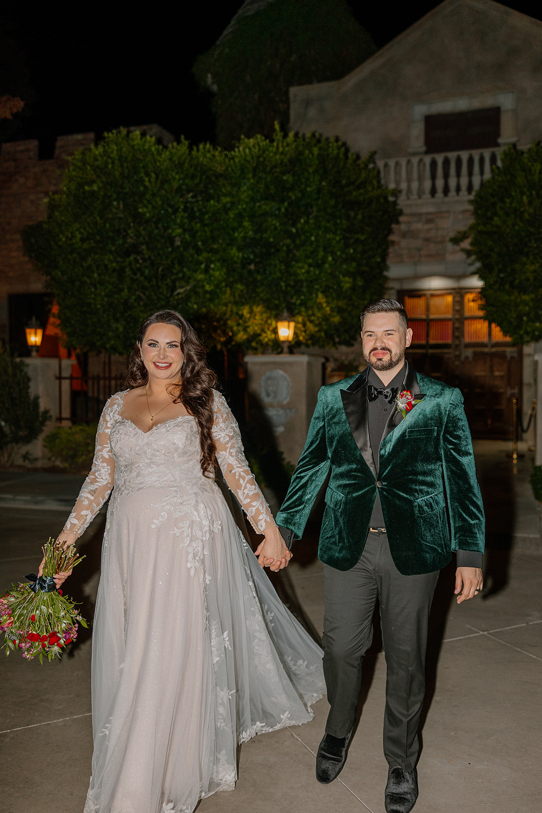 Newlyweds walking hand in hand outside at night after their ceremony.