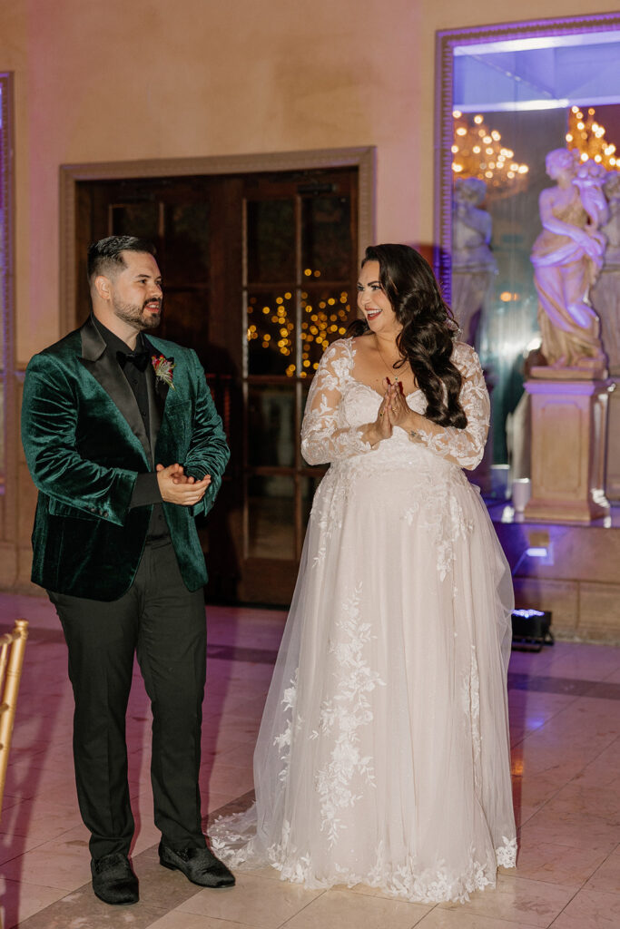 Bride and groom smiling and reacting during reception speeches.