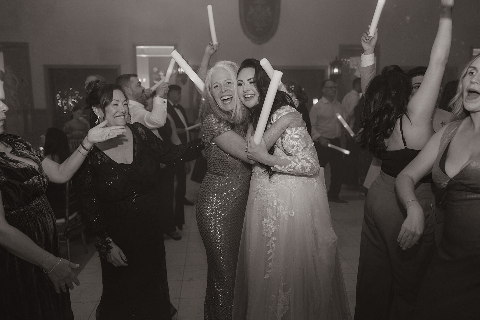 Bride hugging a guest on the dance floor with glow sticks during the reception at a wedding venue in Chandler.