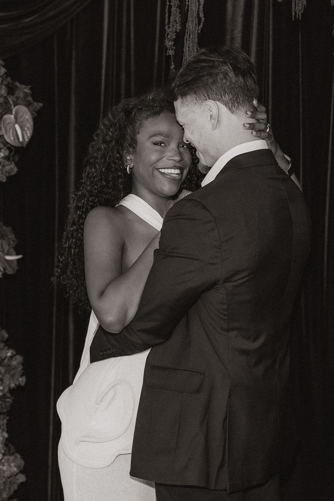 Woman laughs while man hugs her closely during editorial engagement photos. 