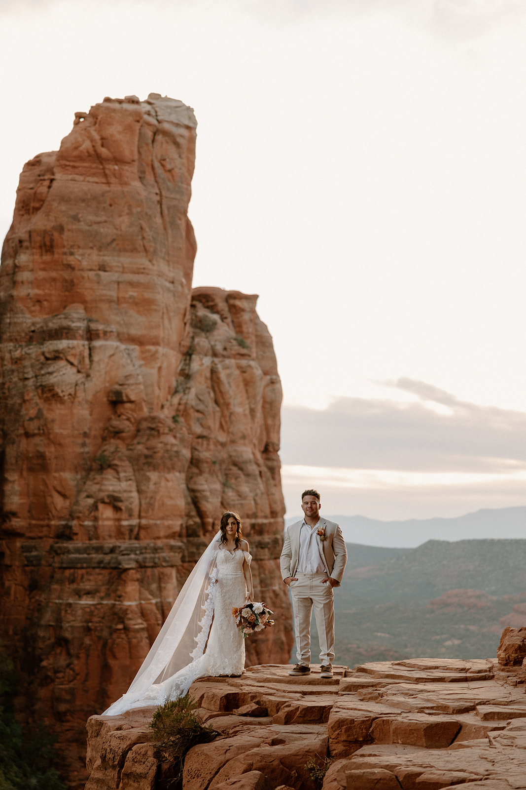 Bride and groom walking along a sandstone ledge as they elope in Arizona.