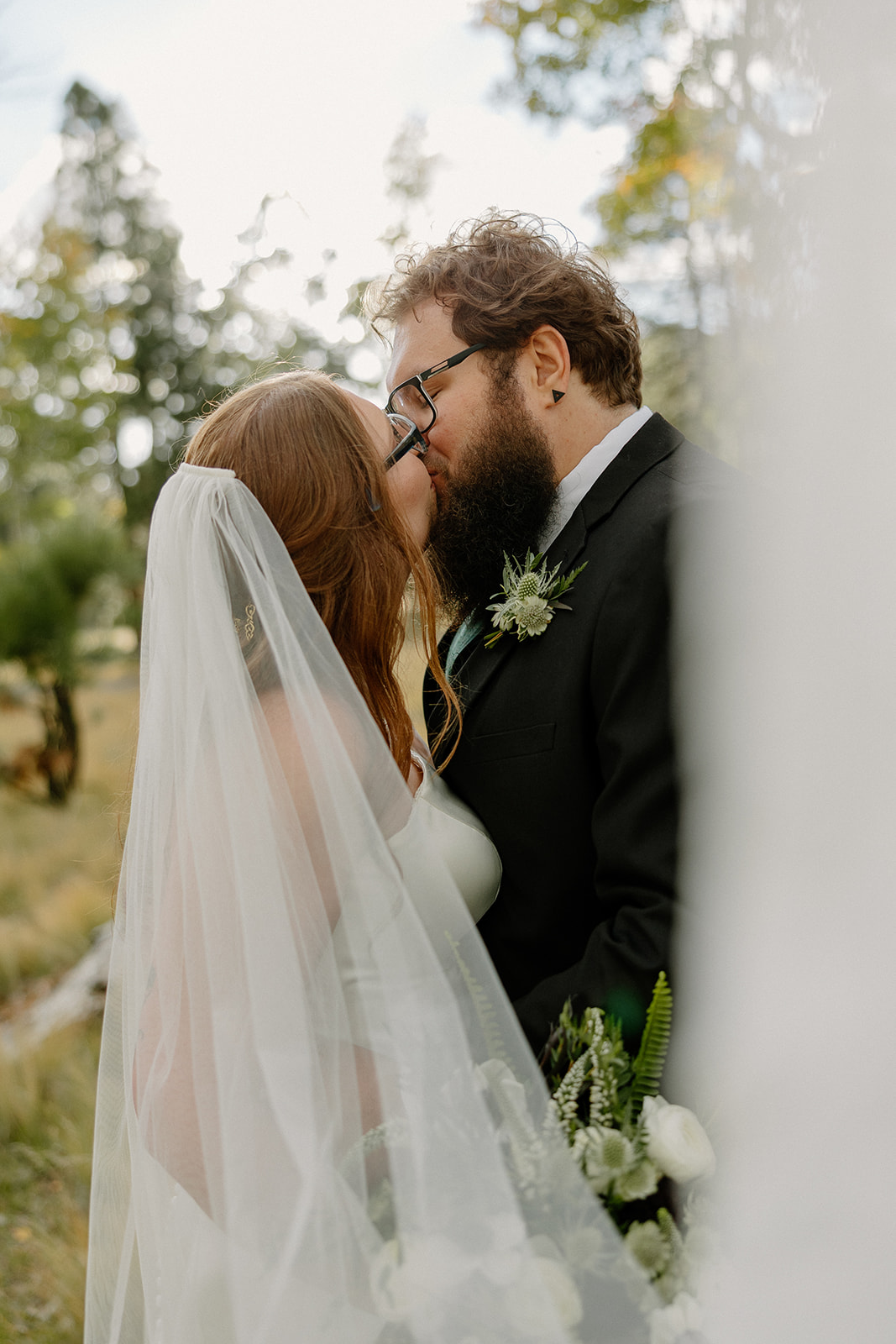 Newlyweds kissing beneath a flowing veil after choosing to elope in Arizona.