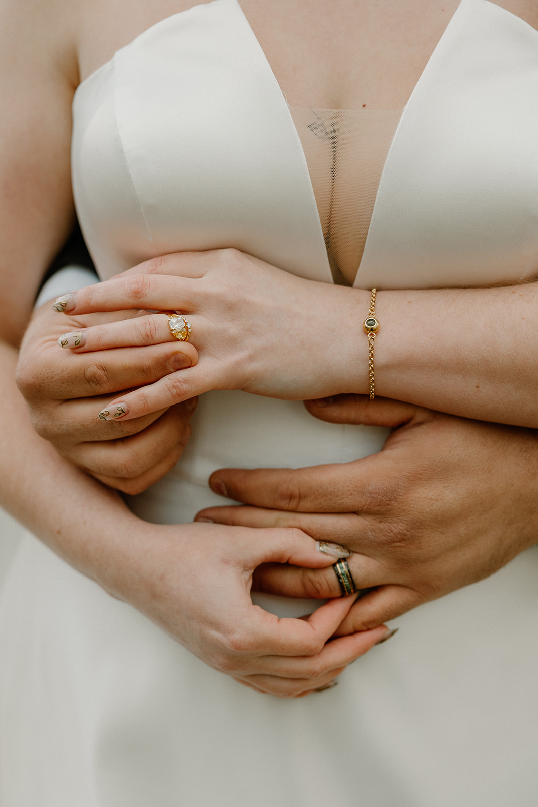 Close-up of bride and groom’s hands showing wedding bands and engagement ring.