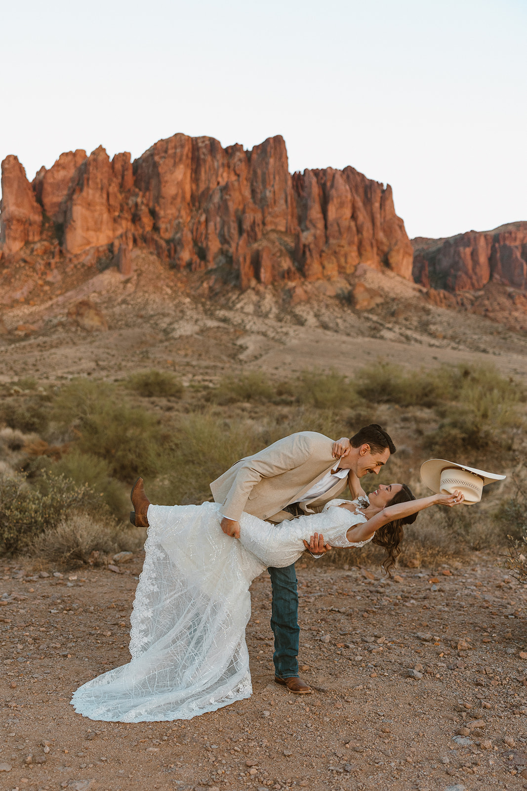 Bride and groom laughing in front of the Superstition Mountains after choosing to elope in Arizona.