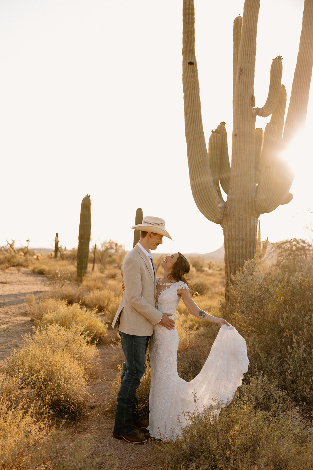 Bride and groom embracing at sunset in front of cactus at beautiful Arizona elopement locations. 