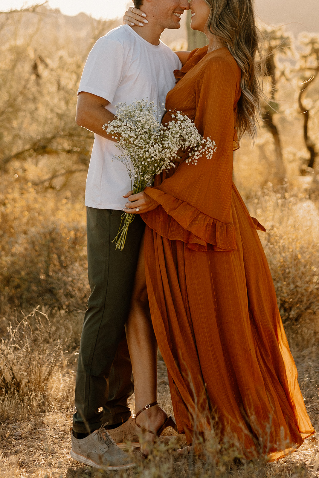 Couple embracing in the desert with bouquet in hand after choosing to elope in Arizona.
