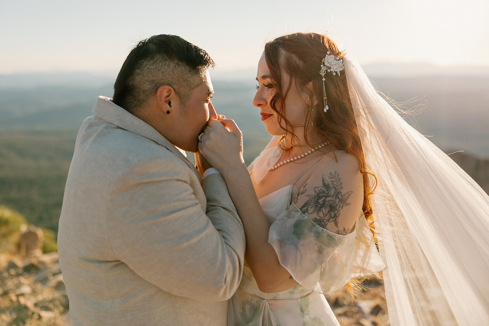 Bride grabs her bride's hands and kisses her hands while looking in her eyes. 