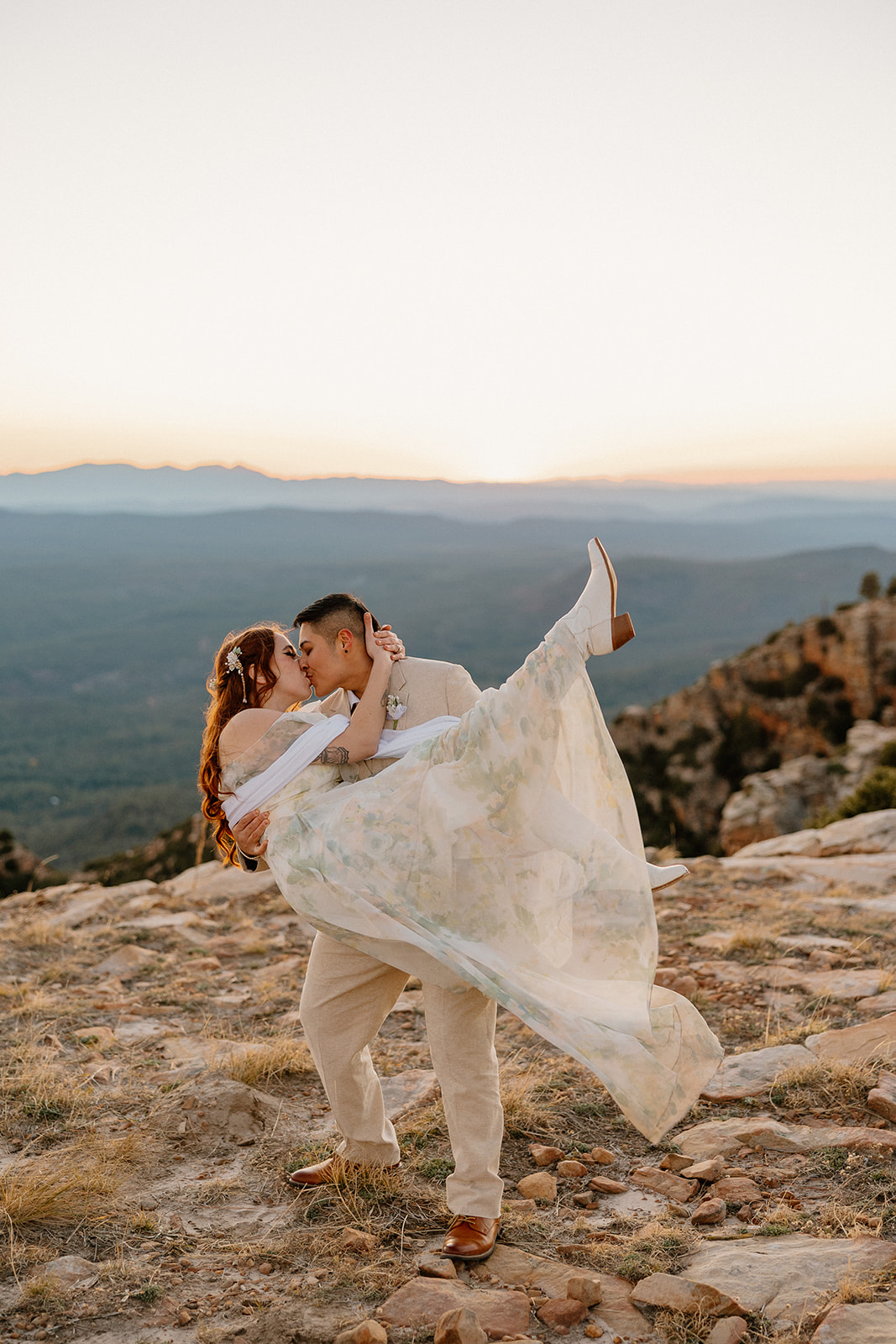 Groom dipping bride at sunset on a cliff edge after they elope in Arizona.