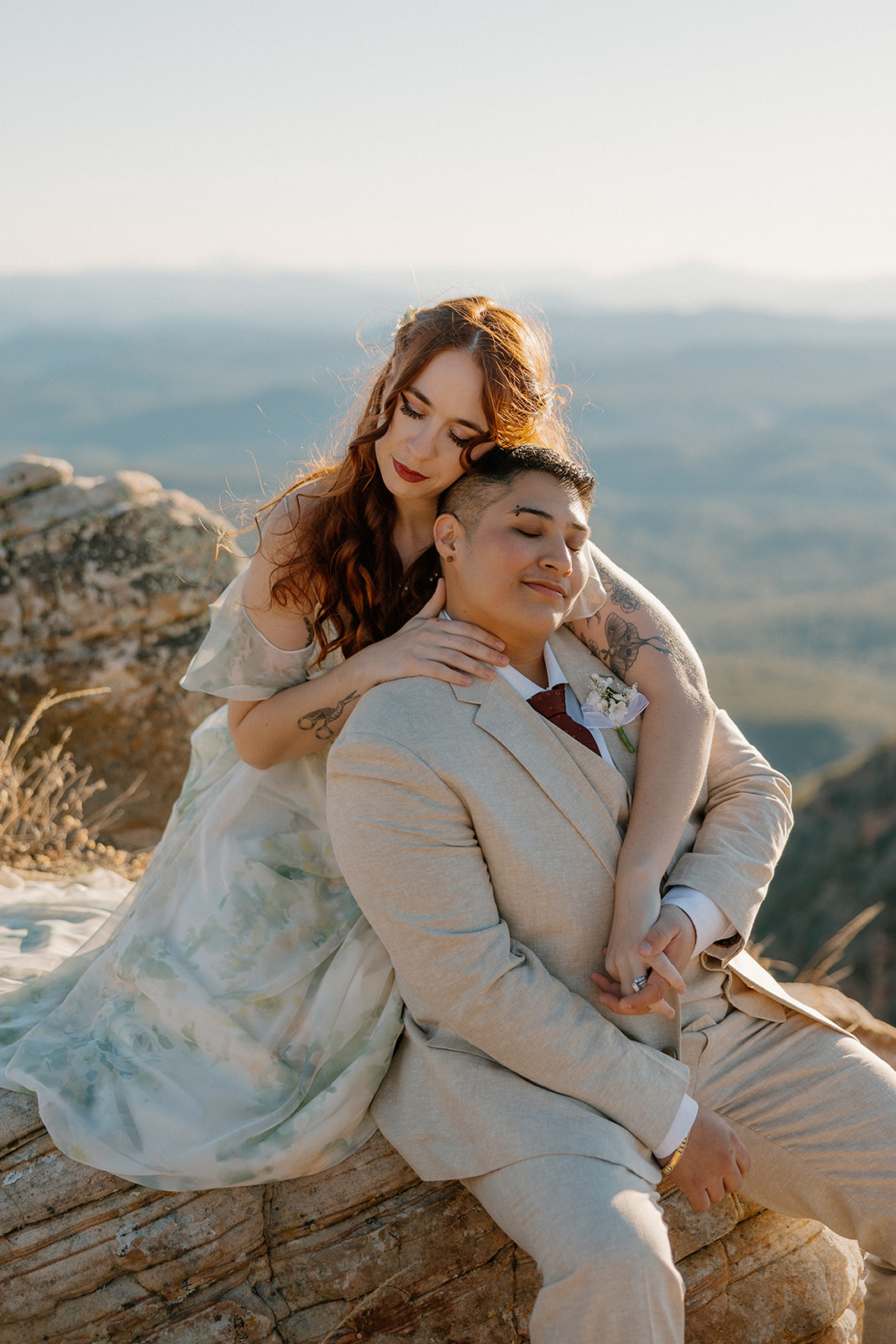 Couple sitting together on cliffside after intimate elopement ceremony. 