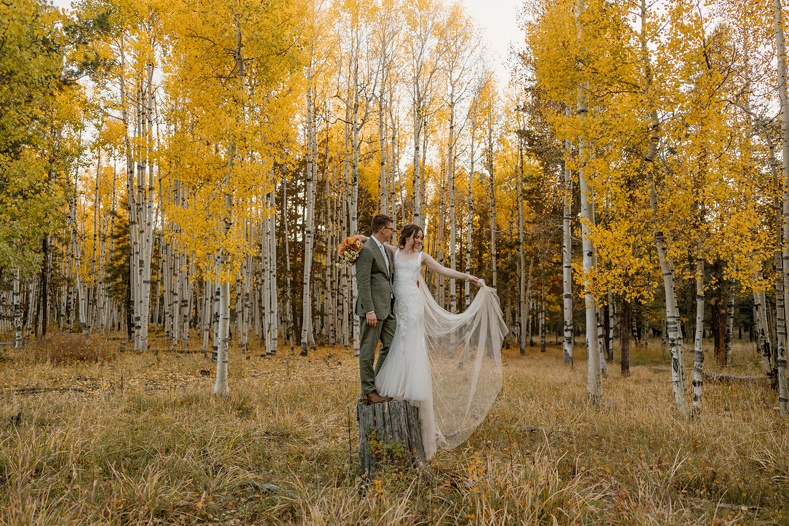Couple standing in a golden aspen grove during a fall elopement in Arizona forest.