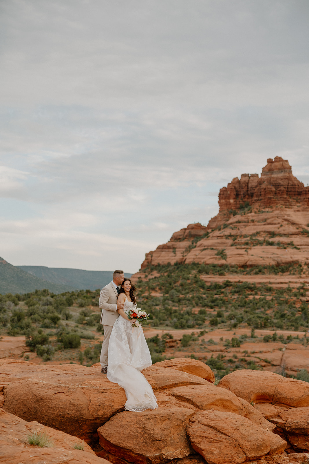 Bride and groom standing on a red rock overlook during their Arizona elopement in Sedona.