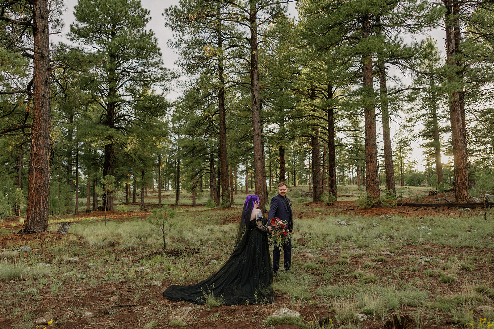 Couple standing together in a wide pine forest clearing during their Arizona elopement.
