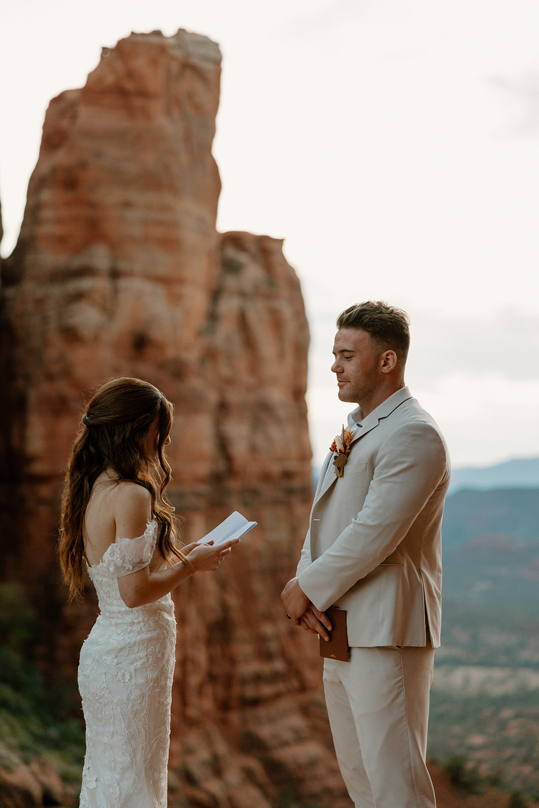 Bride reading vows to groom on a red rock overlook during their Arizona elopement.