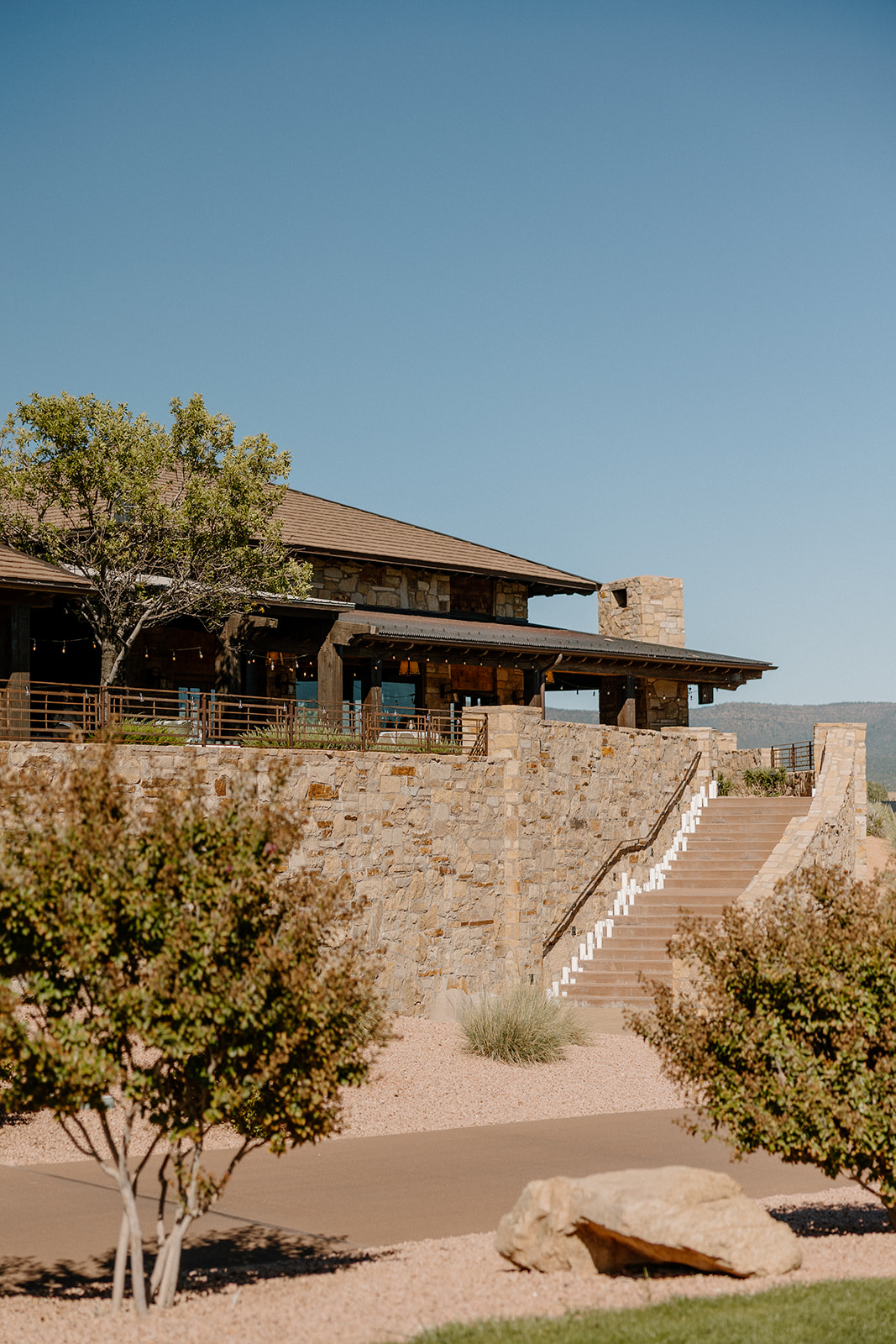 Stone lodge exterior and terrace overlooking the landscape at a Payson wedding venue on a clear day.