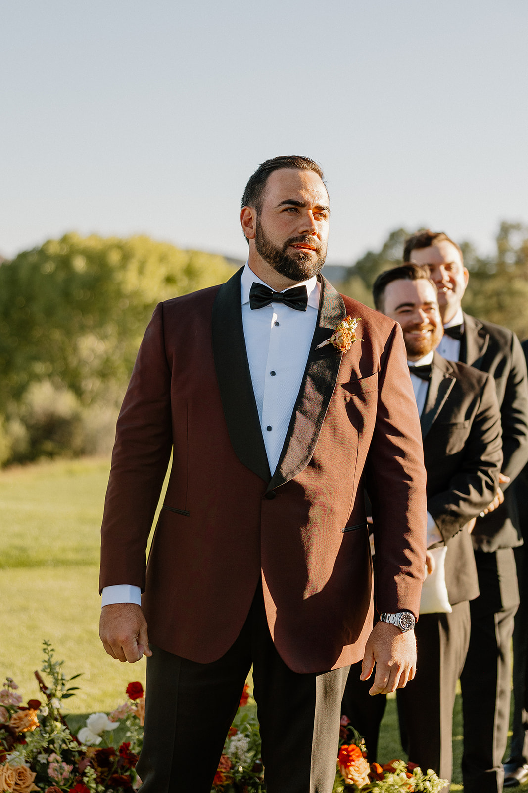 Groom stands at the altar during the ceremony with groomsmen lined up behind him.