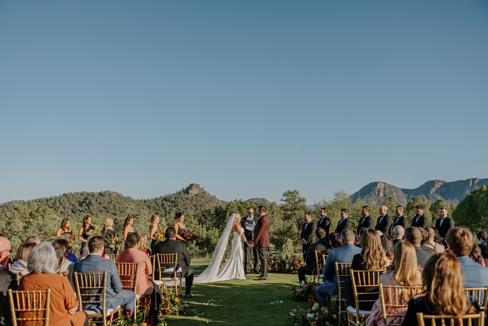 Outdoor wedding ceremony with guests seated on gold chairs and mountain views at a Payson wedding venue.