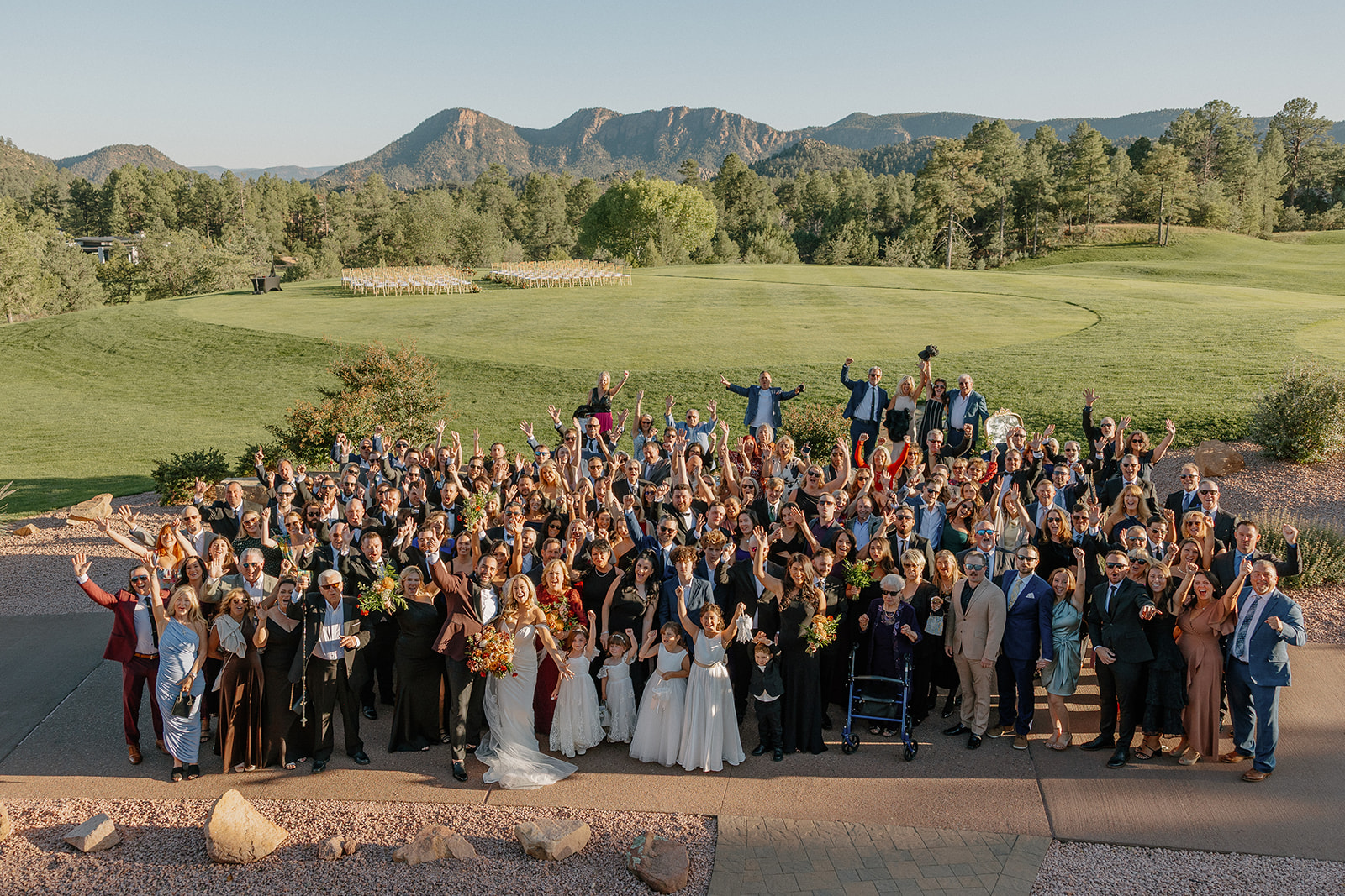 Large group wedding photo with guests cheering against a mountain backdrop at a Payson wedding venue.