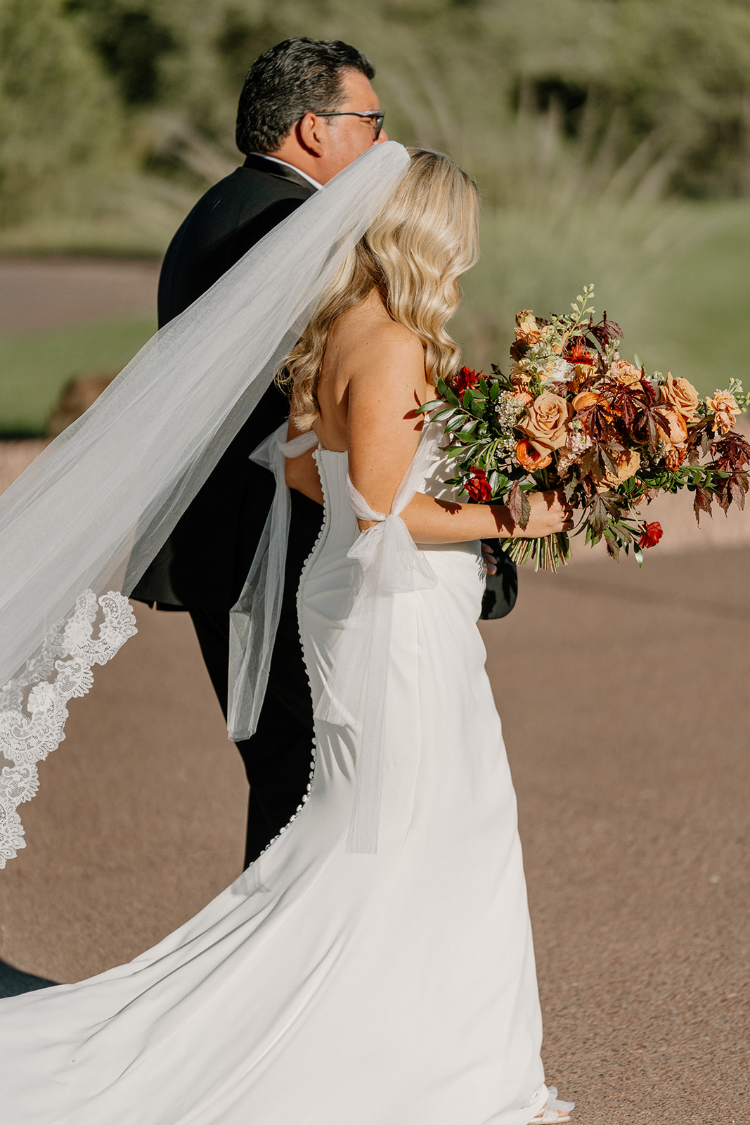 Bride walks with her father while holding a fall-toned bouquet during her ceremony entrance at a Payson wedding venue.