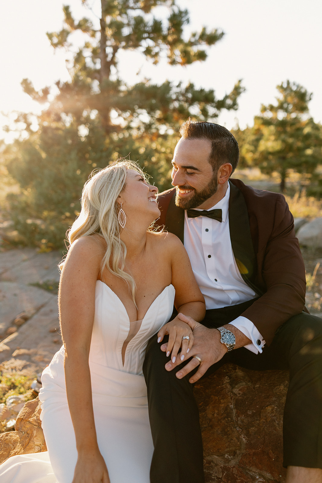 Bride and groom sit together on rocks during golden hour portraits, sharing a quiet moment at a Payson wedding venue.