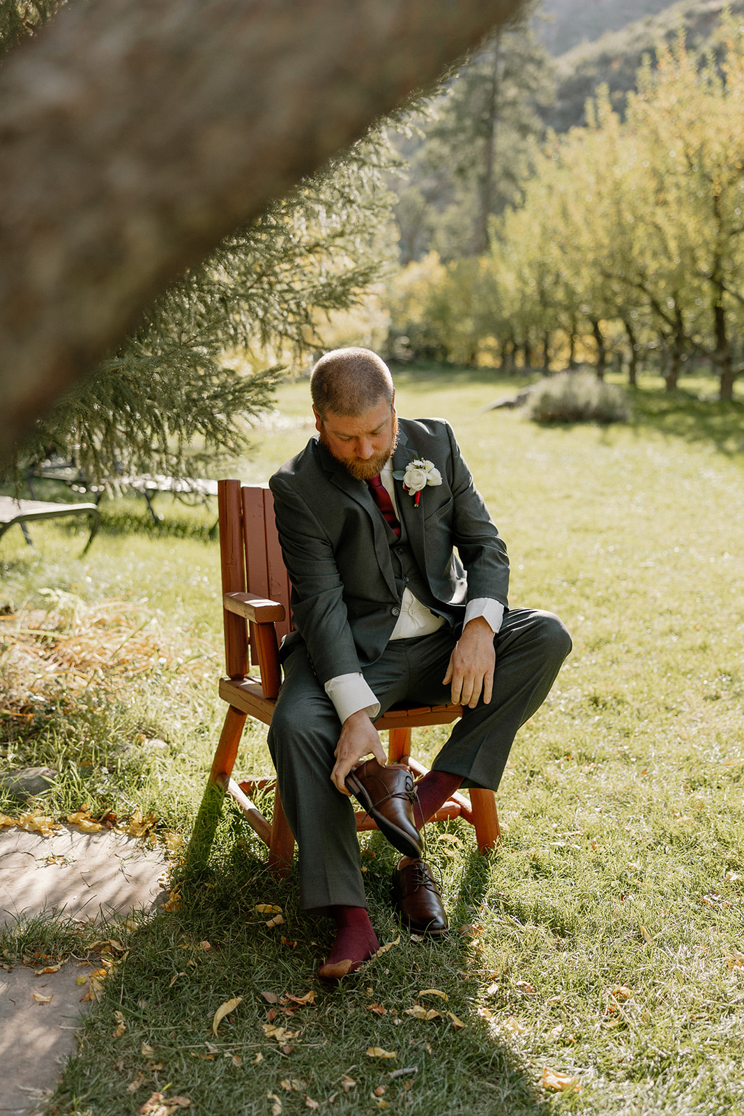 Groom adjusting his shoes while sitting outdoors before the ceremony at a Sedona wedding venue