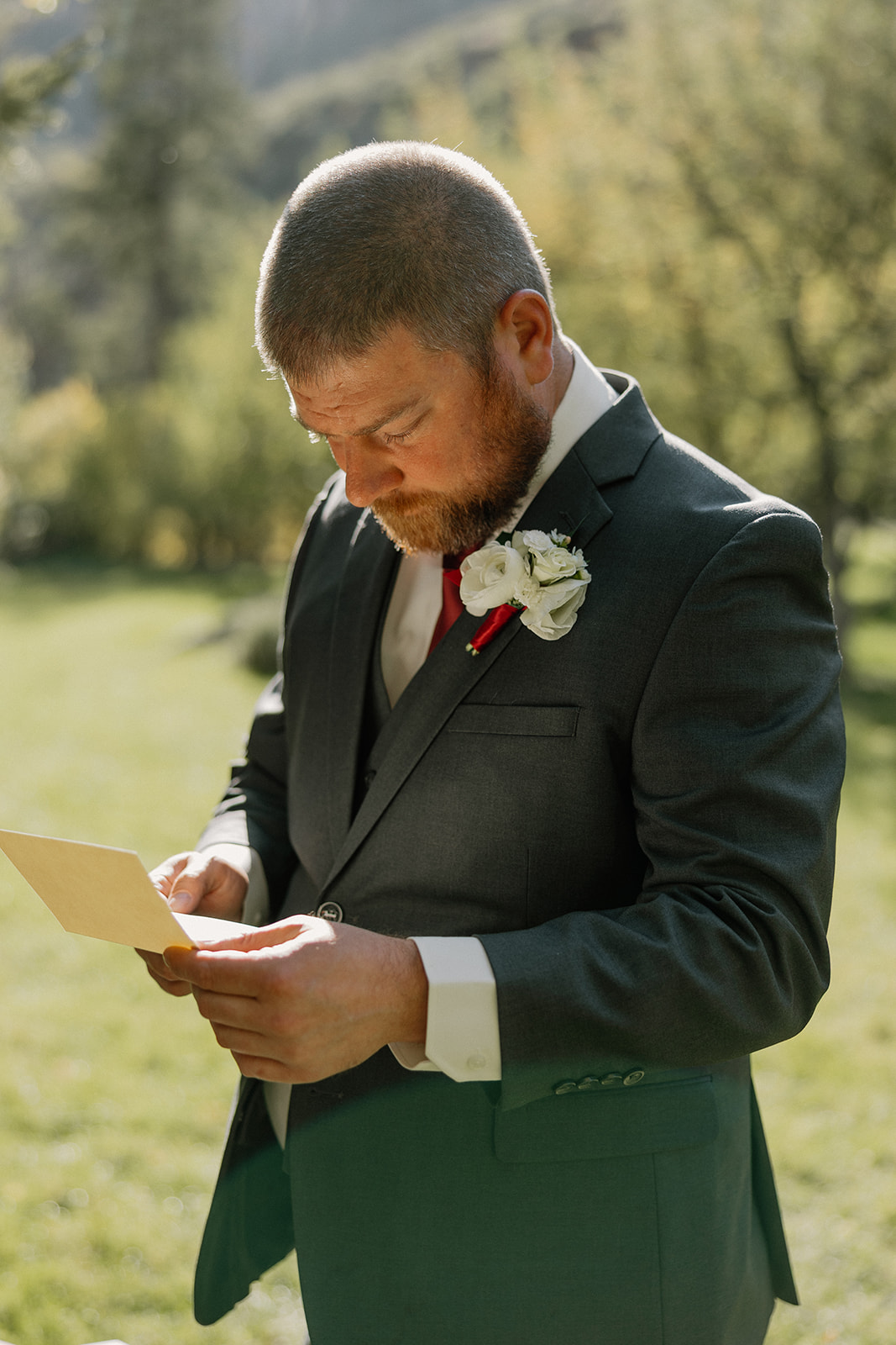 Groom reading a handwritten note before the ceremony in natural afternoon light