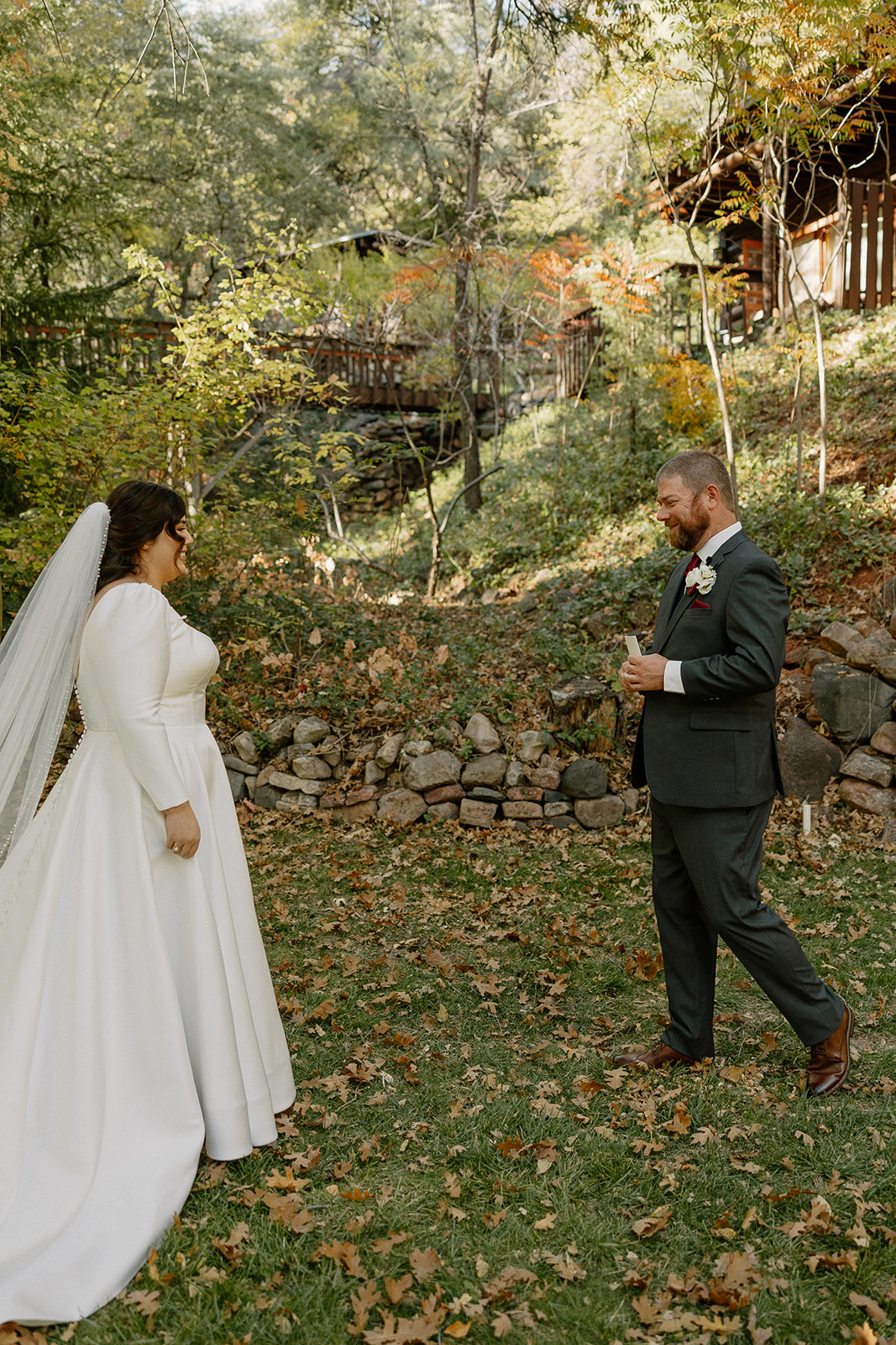 Bride and groom sharing an emotional first look surrounded by fall leaves and trees