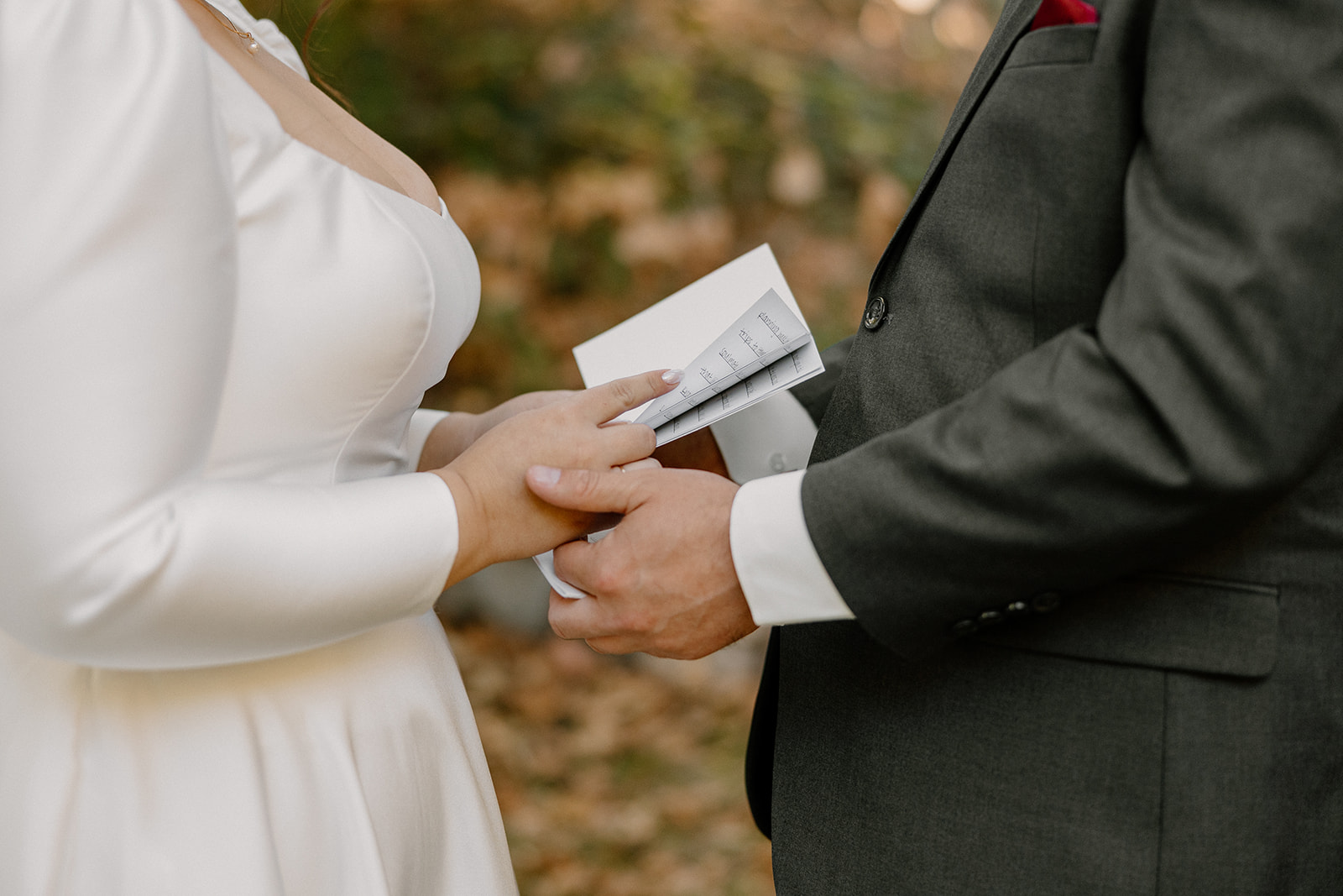 Close-up of bride and groom holding hands while exchanging vows during an outdoor Sedona wedding