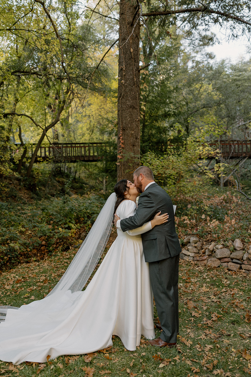 Bride and groom sharing a quiet kiss surrounded by fall trees at a Sedona wedding venue