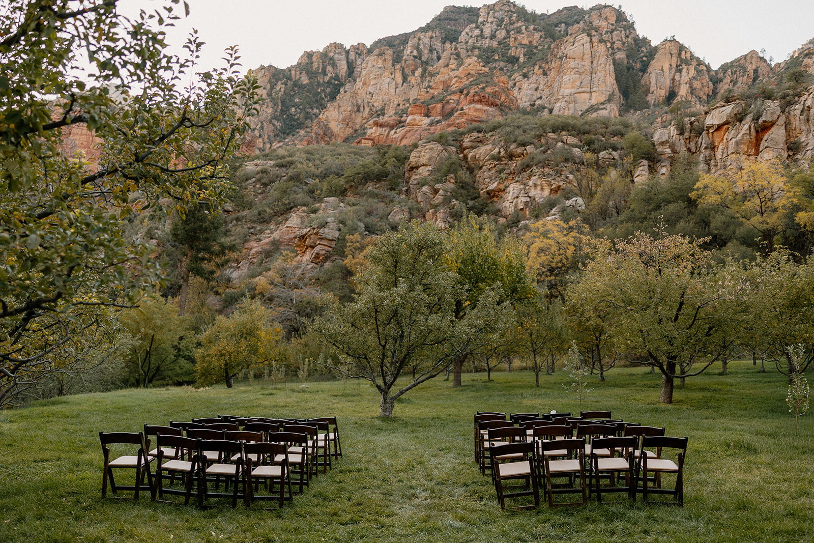Outdoor ceremony setup with wooden chairs facing orchard views at a Sedona wedding venue