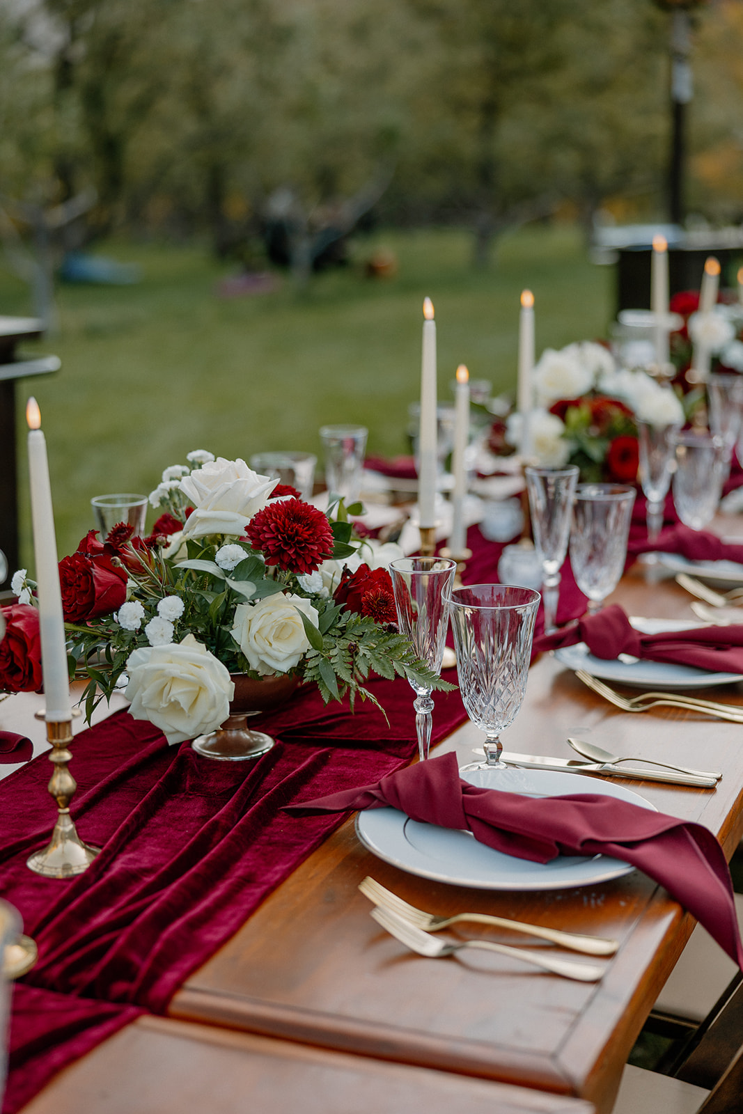 Wedding table decorated with red and white florals and candles at Orchard Canyon on Oak Creek