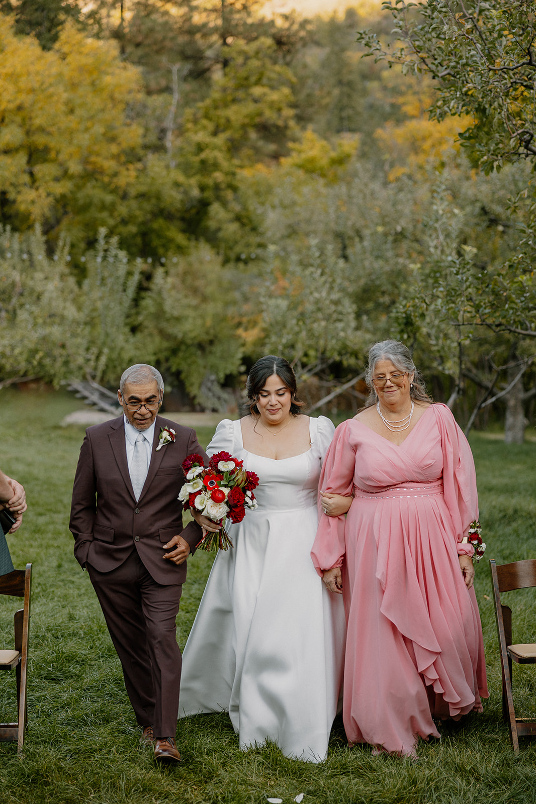 Bride walking down the aisle with her parents during an outdoor wedding in Sedona